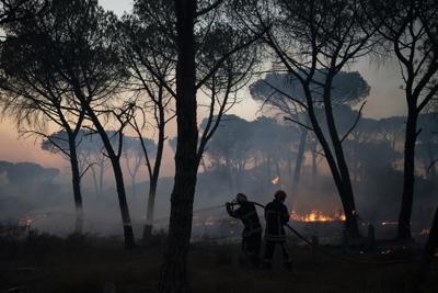 Bomberos emplean una manguera para extinguir un incendio cerca de Le Luc, en el sur de Francia, el 17 de agosto de 2021. (AP Foto/Daniel Cole)