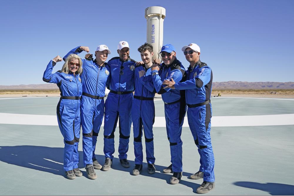 Blue Origin's latest space passengers from left,  Laura Shepard Churchley, Dylan Taylor, Michael Strahan, Cameron Bess, Lane Bess, and Evan Dick pose for a photo in front of the booster rocket at the spaceport near Van Horn, Texas, Saturday, Dec. 11, 2021. (AP Photo/LM Otero)