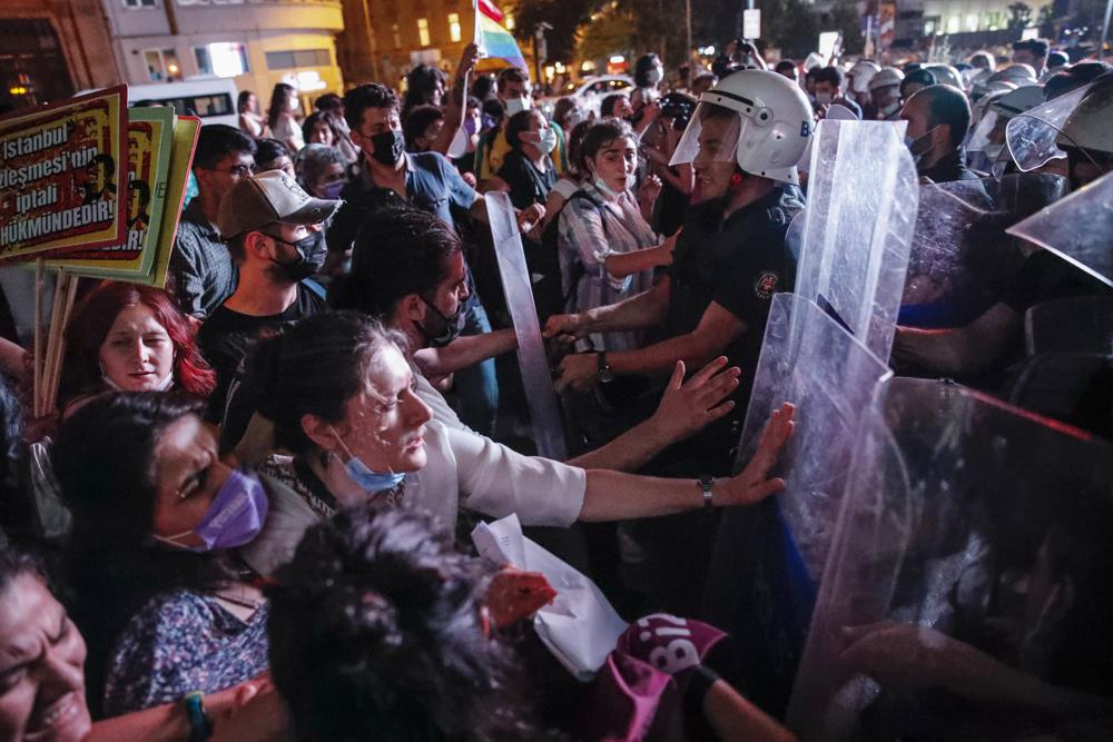 Protesters, left, clash with police officers preventing them from marching against the government's decision to withdraw from Istanbul Convention, in Istanbul, Thursday, July 1, 2021. Turkey formally withdrew Thursday from a landmark international treaty protecting women from violence, and signed in its own city of Istanbul, though President Recep Tayyip Erdogan insisted it won’t be a step backwards for women. Hundreds of women demonstrated in Istanbul later Thursday, holding banners that said they won't give up on the Council of Europe’s Istanbul Convention. (AP Photo/Kemal Aslan)