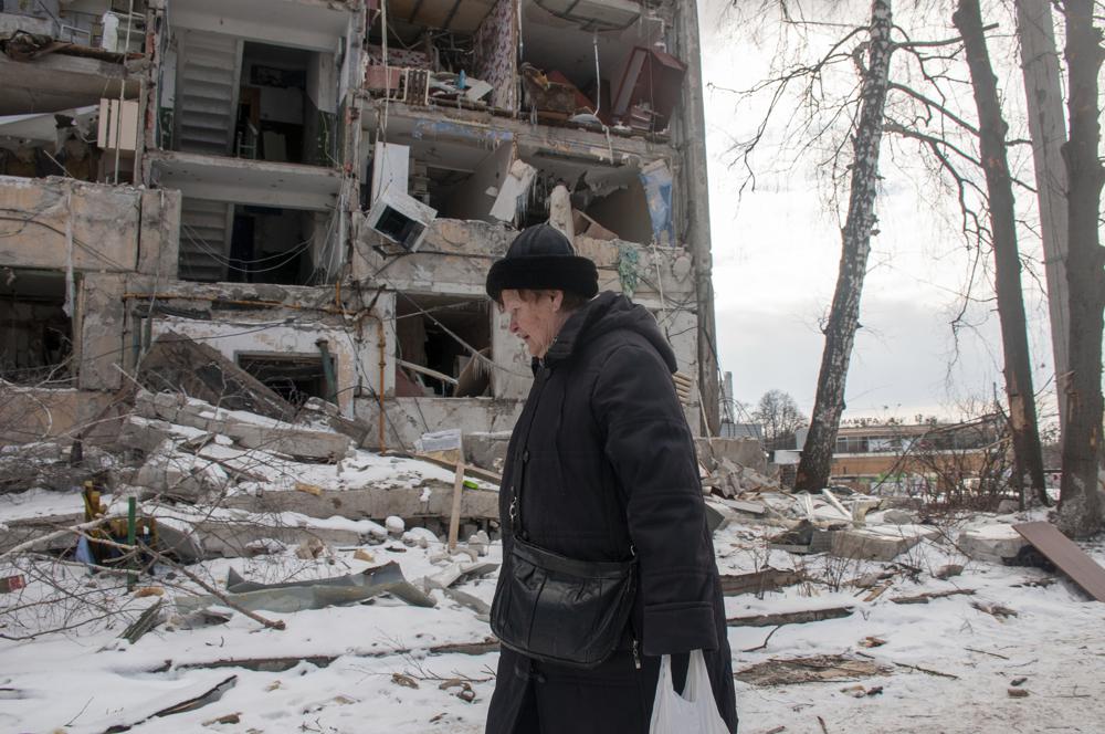 Una mujer pasa junto a un edificio dañado por los bombardeos, en Kharkiv, Ucrania, el domingo 13 de marzo de 2022. (Foto AP/Andrew Marienko)