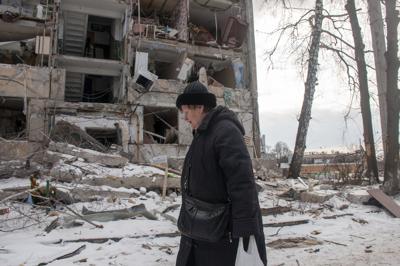 Una mujer pasa junto a un edificio dañado por los bombardeos, en Kharkiv, Ucrania, el domingo 13 de marzo de 2022. (AP Photo/Andrew Marienko)