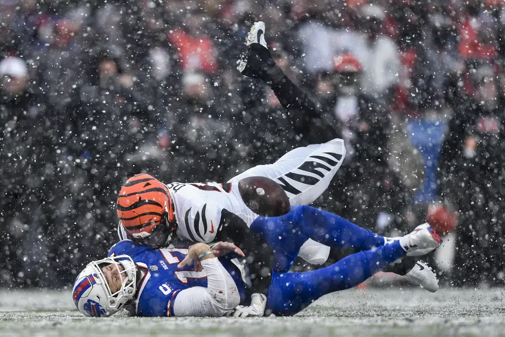 Buffalo Bills quarterback Josh Allen (17) takes a hit from Cincinnati Bengals defensive end Joseph Ossai (58) during the second quarter of an NFL division round football game, Sunday, Jan. 22, 2023, in Orchard Park, N.Y. The play was ruled an incomplete pass. (AP Photo/Adrian Kraus)
