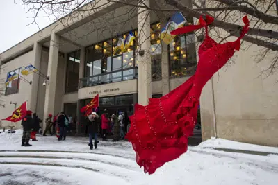 ARCHIVO - Un vestido rojo cuelga de un árbol en el patio del Ayuntamiento de Winnipeg durante una manifestación, el jueves 15 de diciembre de 2022, en Winnipeg, Manitoba, para pedir a la ciudad que cese las operaciones de vertido en el vertedero de Brady y realice una búsqueda de los restos de mujeres indígenas desaparecidas y asesinadas que se cree que están enterradas allí. El viernes 5 de mayo de 2023 se celebra el Día de Concientización sobre los Pueblos Indígenas Desaparecidos y Asesinados, un día solemne destinado a llamar más la atención sobre el número desproporcionado de personas indígenas que han desaparecido o han enfrentado violencia. (Daniel Crump/The Canadian Press vía AP, Archivo)