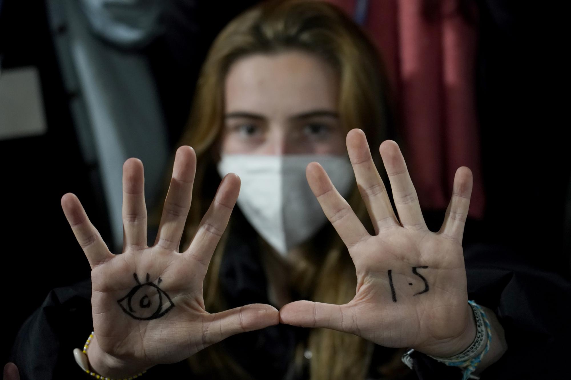 FILE - A youngster, with an eye drawn on her hand to show she is watching and 1.5 for countries to keep warming below 1.5 degrees Celsius, takes part in a Fridays for Future climate protest inside a plenary corridor at the SEC (Scottish Event Campus) venue for the COP26 U.N. Climate Summit, in Glasgow, Scotland, Wednesday, Nov. 10, 2021. The United Nations on Monday, Feb. 28, 2022, released a new report on climate change. (AP Photo/Alberto Pezzali, File)