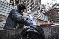 Hoda, 57, a Lebanese garbage scavenger, searches in a dumpster in Beirut, Lebanon, Saturday, Jan. 13, 2022. As Lebanon faces one of the world’s worst financial crises in modern history, now even its trash has become a commodity fought over in the street. (AP Photo/Lujain Jo)