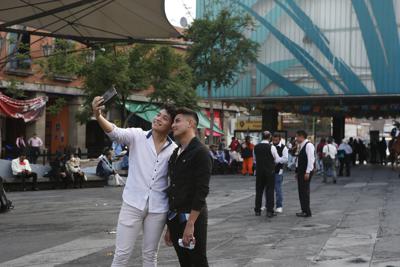 Dos jóvenes se toman una selfie el sábado 10 de julio de 2021 en la Plaza Garibaldi de la Ciudad de México. (AP Foto/Ginnette Riquelme)