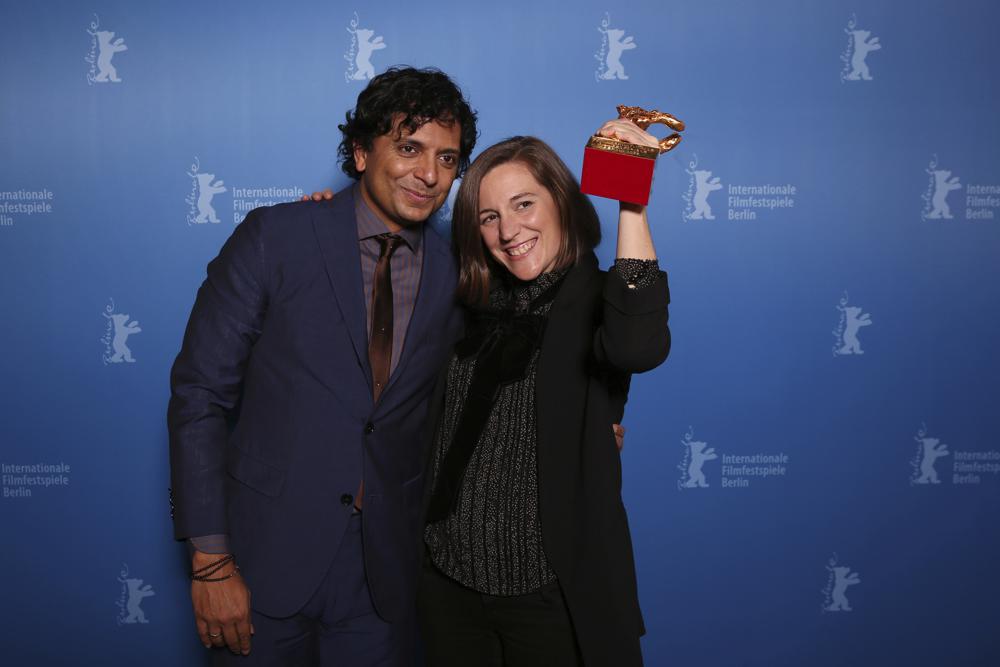 El presidente del jurado de la Berlinale 2022 M. Night Shyamalan izquierda y la directora y guionista española Carla Simón posan con el Oso de Oro durante una sesión fotográfica tras recibir el Oso de Plata del jurado por su película “Manto de gemas” durante la ceremonia de premiación del Festival Internacional de Cine de Berlín en Berlín, Alemania, el 16 de febrero de 2022. (Ronny Hartmann/Pool via AP)
