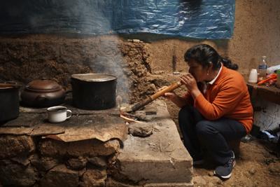 La futura primera dama de Perú, Lilia Paredes, de 48 años, sopla aire a través de un junco hueco para encender su estufa de leña el jueves 22 de julio de 2021, en su casa de adobe en la localidad rural de Chugur, Perú. (AP Foto/Franklin Briceño)