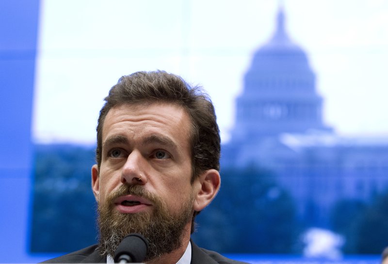 Twitter CEO speaking into a microphone with an image of the White House behind him