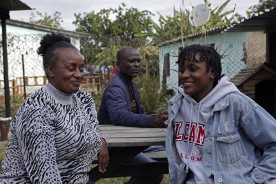 Andrew Ngwenya, centro, su esposa De-egma, izquierda, y su hija en un municipio de clase trabajadora en Harare, la capital de Zimbabue, el lunes 12 de julio de 2021. (AP Foto/Tsvangirayi Mukwazhi)