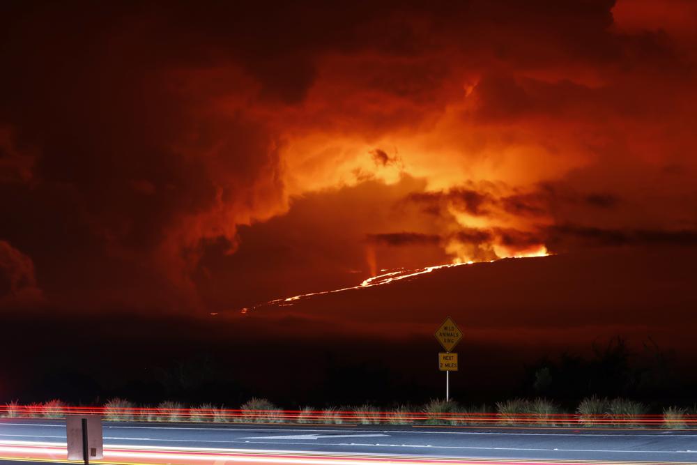 En esta fotogafía automóviles pasan frente al volcán Mauna Loa en erupción, el lunes 28 de noviembre de 2022, cerca de Hilo, Hawai. (AP Foto/Marco García)