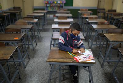 Sebastián, de 7 años, asiste solo a la clase de matemáticas el primer día de regreso a la escuela presencial desde el inicio de las restricciones por la pandemia de COVID-19 en la escuela municipal Andrés Bello en Caracas, Venezuela, el lunes 25 de octubre de 2021. (AP Foto/Ariana Cubillos)