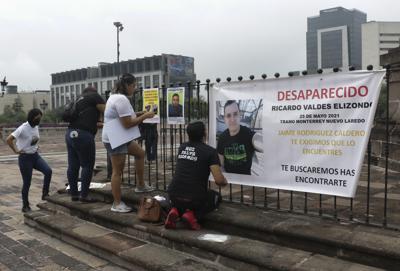 Familiares de Ricardo Valdés, quien el 25 de mayo desapareció en un tramo de una carretera que comunica la ciudad mexicana de Monterrey con la ciudad fronteriza de Nuevo Laredo, coloca carteles con sus fotografías en Monterrey, México, el jueves 24 de junio de 2021. Hasta 50 personas han desaparecido después de emprender viajes sencillos por esa carretera densamente transitada, apodada como "la carretera de la muerte". (AP Foto/Roberto Martínez)