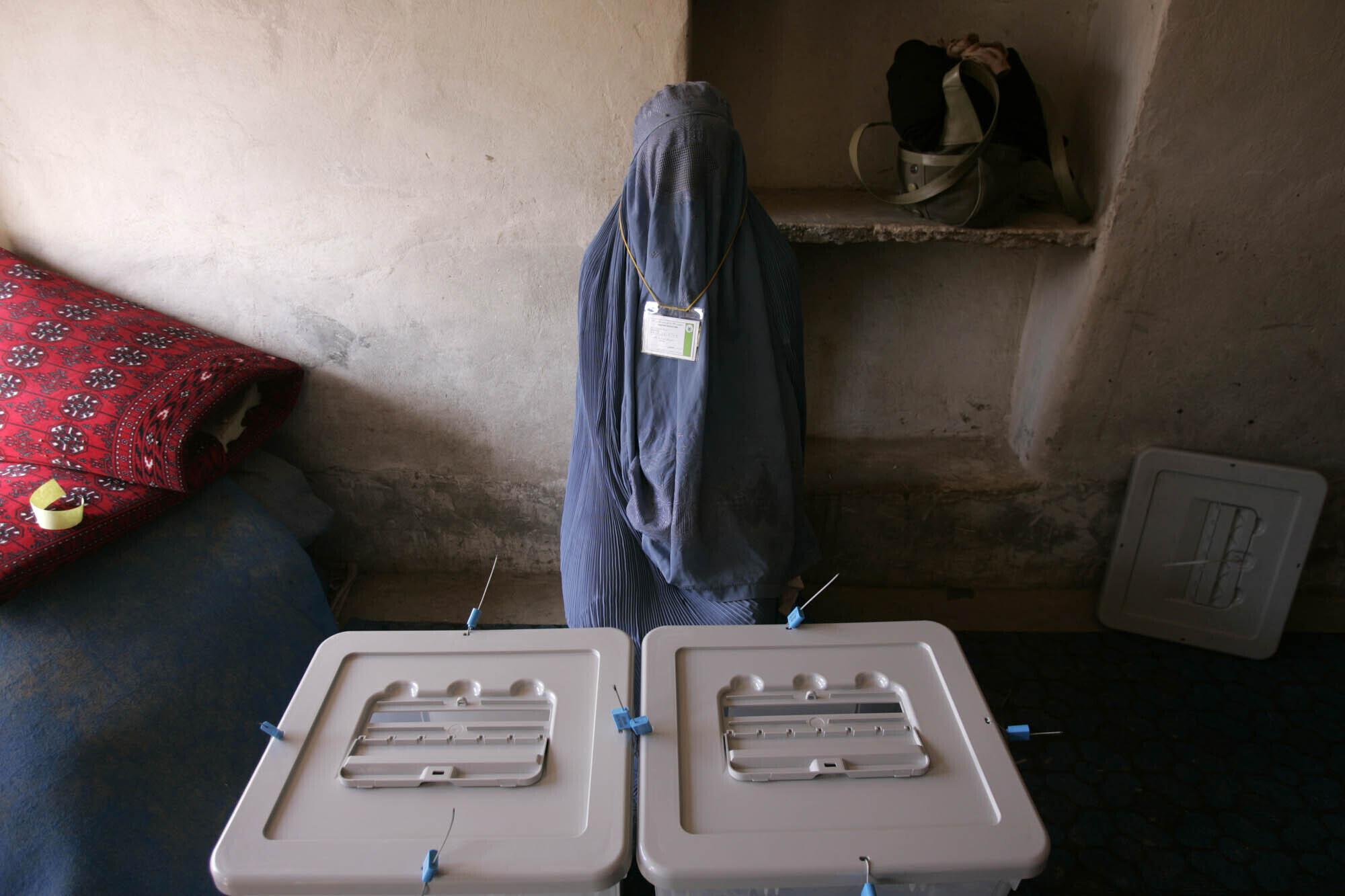 A woman poll worker waits for voters to arrive at a polling station in Kandahar, Afghanistan, Sept. 18, 2005. Afghanistan held landmark parliamentary elections, the first in three decades. (AP Photo/Saurabh Das)