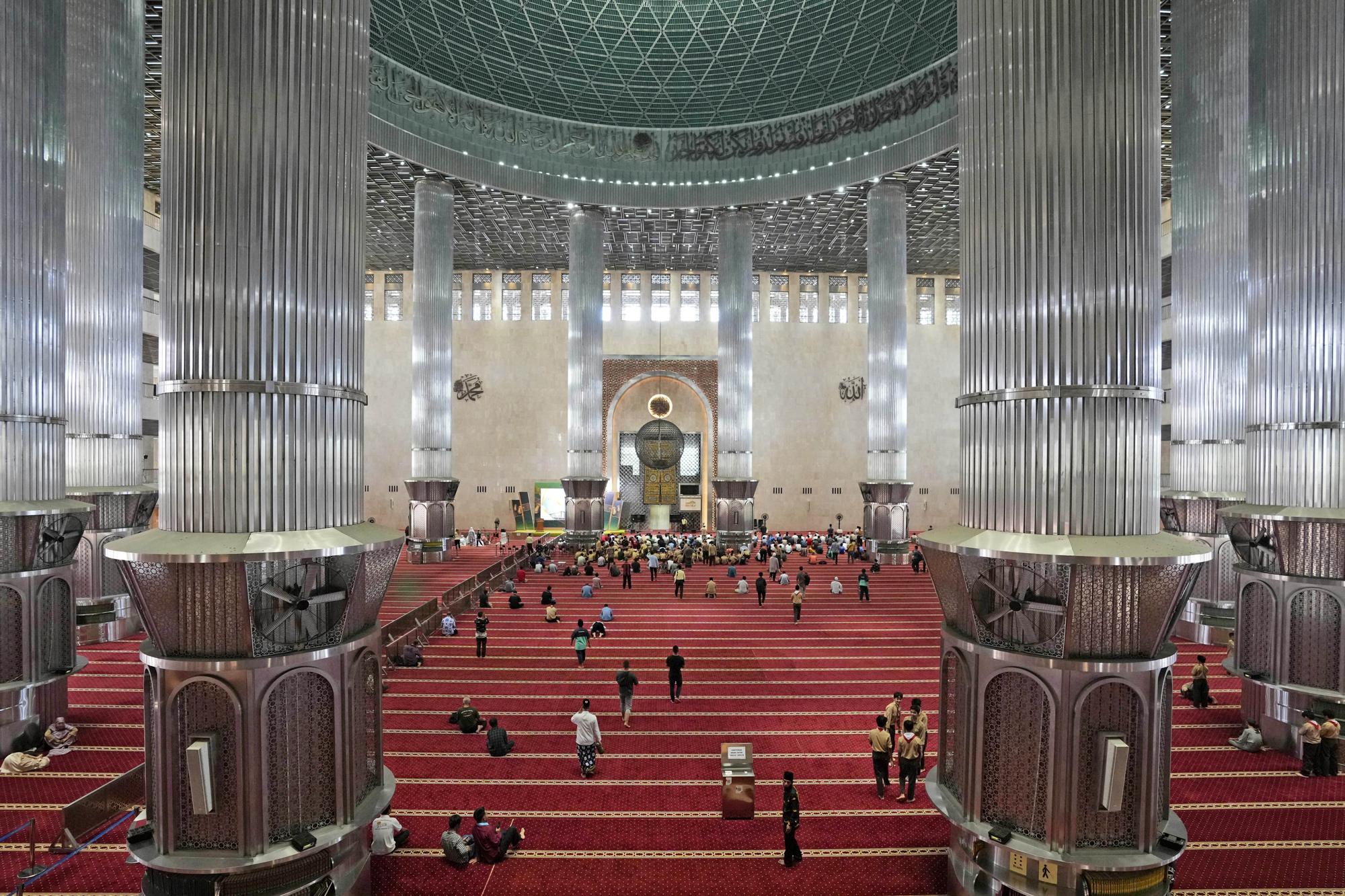 La gente llega para la oración del mediodía en la Mezquita Istiqlal, cuya electricidad proviene parcialmente de energía solar, en Yakarta, Indonesia, el miércoles 29 de marzo de 2023. Una importante renovación en 2019 instaló más de 500 paneles solares en el amplio techo de la mezquita, ahora un importante y limpio fuente de electricidad de Istiqlal.  (Foto AP/Tatán Syuflana)