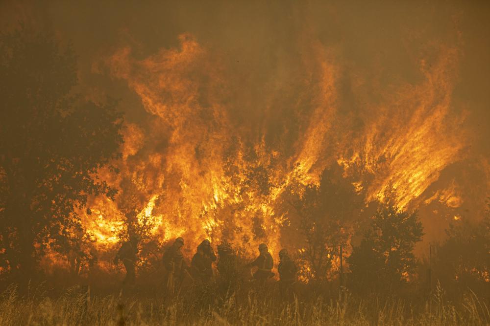 Firefighters work in front of flames during a wildfire in the Sierra de la Culebra in the Zamora Provence on Saturday June 18, 2022. Thousands of hectares of wooded hill land in northwestern Spain have been burnt by a wildfire that forced the evacuation of hundreds of people from nearby villages. Officials said the blaze in the Sierra de Culebra mountain range started Wednesday during a dry electric storm. (Emilio Fraile/Europa Press via AP)