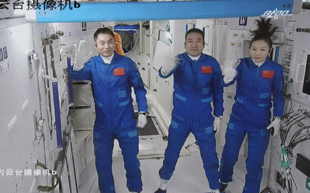 In this photo released by Xinhua News Agency, screen image captured at Beijing Aerospace Control Center in Beijing, China, Saturday, Oct. 16, 2021 shows three Chinese astronauts, from left, Ye Guangfu, Zhai Zhigang and Wang Yaping waving after entering the space station core module Tianhe. China's Shenzhou-13 spacecraft carrying three Chinese astronauts on Saturday docked at its space station, kicking off a record-setting six-month stay as the country moves toward completing the new orbiting outpost. Chinese characters,  left, read "Platform Camera B." (Tian Dingyu/Xinhua via AP)