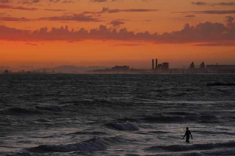 FILE - A man wades into the ocean at sunset on June 22, 2021, in Newport Beach, Calif. The National Oceanic and Atmospheric Administration announced Friday, June 3, 2022, that the amount of carbon dioxide in the atmosphere in May averaged 421 parts per million, more than 50% higher than pre-industrial levels. The NOAA said carbon dioxide levels in the air in May have reached a point last known when Earth was 7 degrees hotter, millions of years ago. (AP Photo/Jae C. Hong, File)