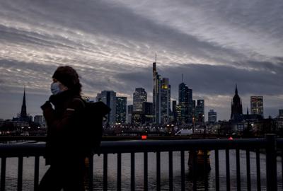 Una mujer con mascarilla pasa caminando mientras al fondo se observa la ciudad de Fráncfort, Alemania, en esta fotografía de archivo del 13 de enero de 2021. (AP Foto/Michael Probst)