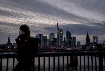 Una mujer con mascarilla pasa caminando mientras al fondo se observa la ciudad de Fráncfort, Alemania, en esta fotografía de archivo del 13 de enero de 2021. (AP Foto/Michael Probst)