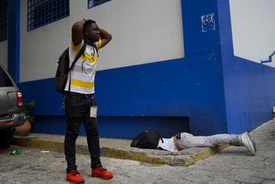 El periodista haitiano Romelo Vilsaint, quien falleció tras ser baleado, yace boca abajo en el estacionamiento de un departamento policial de Puerto Príncipe, Haití, el domingo 30 de octubre de 2022. (AP Foto)