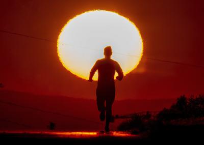 Un hombre corre monte arriba por una estrecha carretera en Fráncfort, Alemania, al amanecer, el 17 de junio de 2022. (AP Foto/Michael Probst)