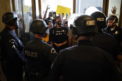 Un grupo de manifestantes corea lemas mientras confronta a la policía a la entrada del ayuntamiento de Los Ángeles el 18 de octubre del 2022. Lo manifestantes demandaron que el concejo municipal suspendiese su reunión virtual hasta que dos de sus miembros renuncien por comentarios racistas. (AP Foto/Jae C. Hong)