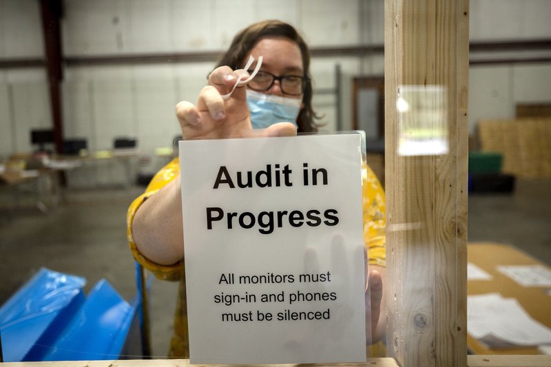 A Chatham County election official posts a sign in the public viewing area before the start of a ballot audit, Friday, Nov. 13, 2020, in Savannah, Ga. Election officials in Georgia’s 159 counties are undertaking a hand tally of the presidential race that stems from an audit required by state law. (AP Photo/Stephen B. Morton)