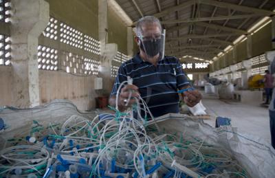 José Antonio Soto, presidente de la Cooperativa Atres, muestra las materias primas utilizadas para la elaboración de madera ecológica en Matanzas, Cuba, el lunes 21 de junio de 2021. (AP Foto/Ismael Francisco)