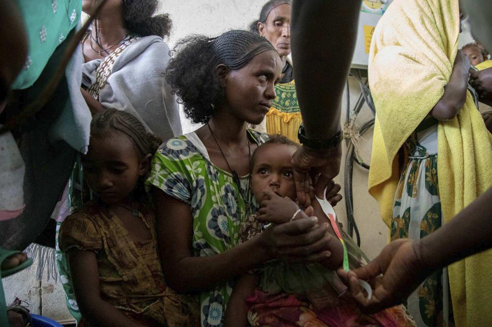 A woman holds a child during a screening for malnutrition in pregnant and lactating women by UNICEF and partners in Gijet in the Tigray region of northern Ethiopia Tuesday, July 20, 2021. For months, the United Nations has warned of famine in Tigray and now internal documents and witness accounts reveal the first starvation deaths since Ethiopia's government in June imposed what the U.N. calls "a de facto humanitarian aid blockade." (Christine Nesbitt/UNICEF via AP)