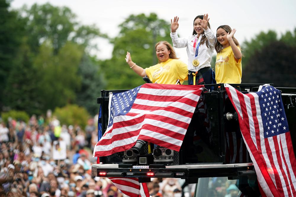 FILE - Olympian Sunisa Lee, center, waves from a St. Paul fire truck with her mom Yeev Thoj, left, and sister Shyenne Lee as fans cheer for her along the parade route, Aug. 8, 2021, in St. Paul, Minn. (Jerry Holt/Star Tribune via AP, File)