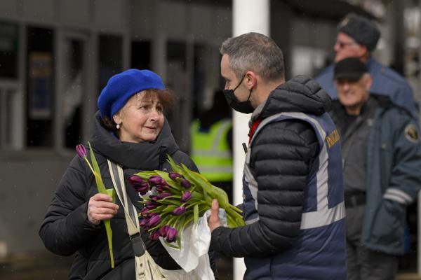 A Romanian Immigrations officer gives flowers to a refugee fleeing the conflict from neighboring Ukraine after she crossed the border on International Women's Day, at the Romanian-Ukrainian border, in Siret, Romania, Tuesday, March 8, 2022. (AP Photo/Andreea Alexandru)