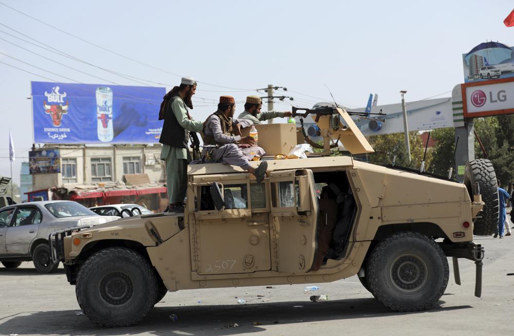 Taliban fighters stand guard in front of the Hamid Karzai International Airport, in Kabul, Afghanistan, Monday, Aug. 16, 2021. Thousands of people packed into the Afghan capital's airport on Monday, rushing the tarmac and pushing onto planes in desperate attempts to flee the country after the Taliban overthrew the Western-backed government. (AP Photo/Rahmat Gul)