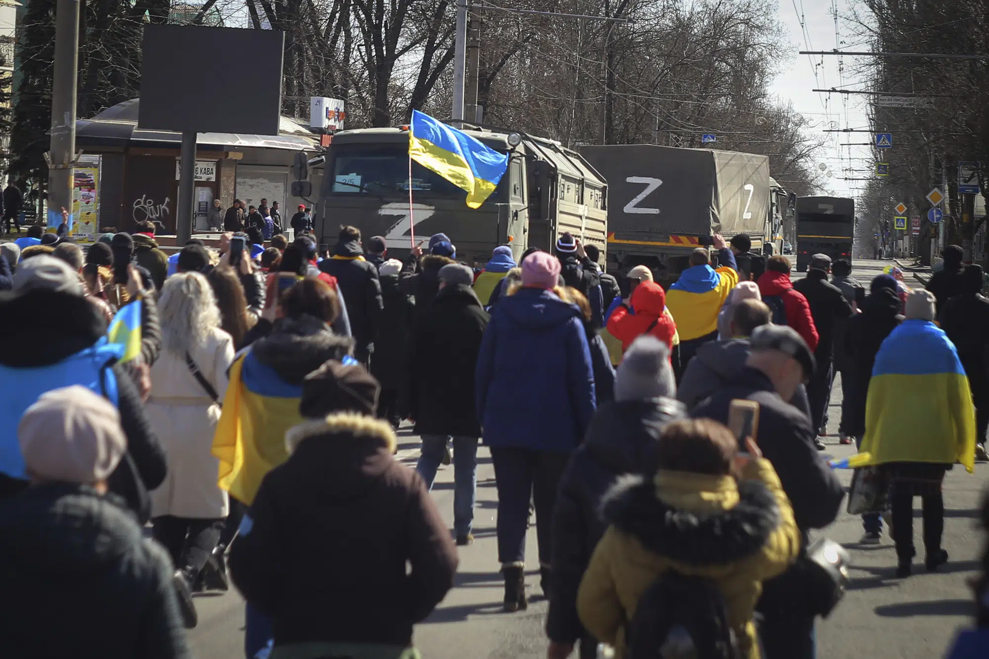 FILE - People with Ukrainian flags walk towards Russian army trucks during a rally against the Russian occupation in Kherson, Ukraine, on March 20, 2022. As Russian forces sought to tighten their hold on Melitopol, hundreds of residents took to the streets to demand the mayor's release. (AP Photo/Olexandr Chornyi, File)