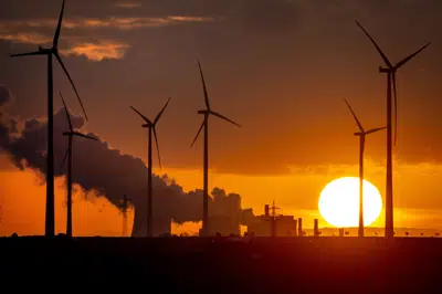 FILE - Steam rises from the coal-fired power plant near wind turbines in Niederaussem, Germany, as the sun rises on Nov. 2, 2022. Germany, a strong advocate of clean energy, turned to coal and oil to address its short term power needs. (AP Photo/Michael Probst, File)