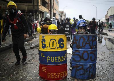 En esta imagen del 9 de junio de 2021, manifestantes antigubernamentales se resguardan detrás de escudos de fabricación casera durante enfrentamientos con la policía en Bogotá.  (AP Foto/Iván Valencia, Archivo)