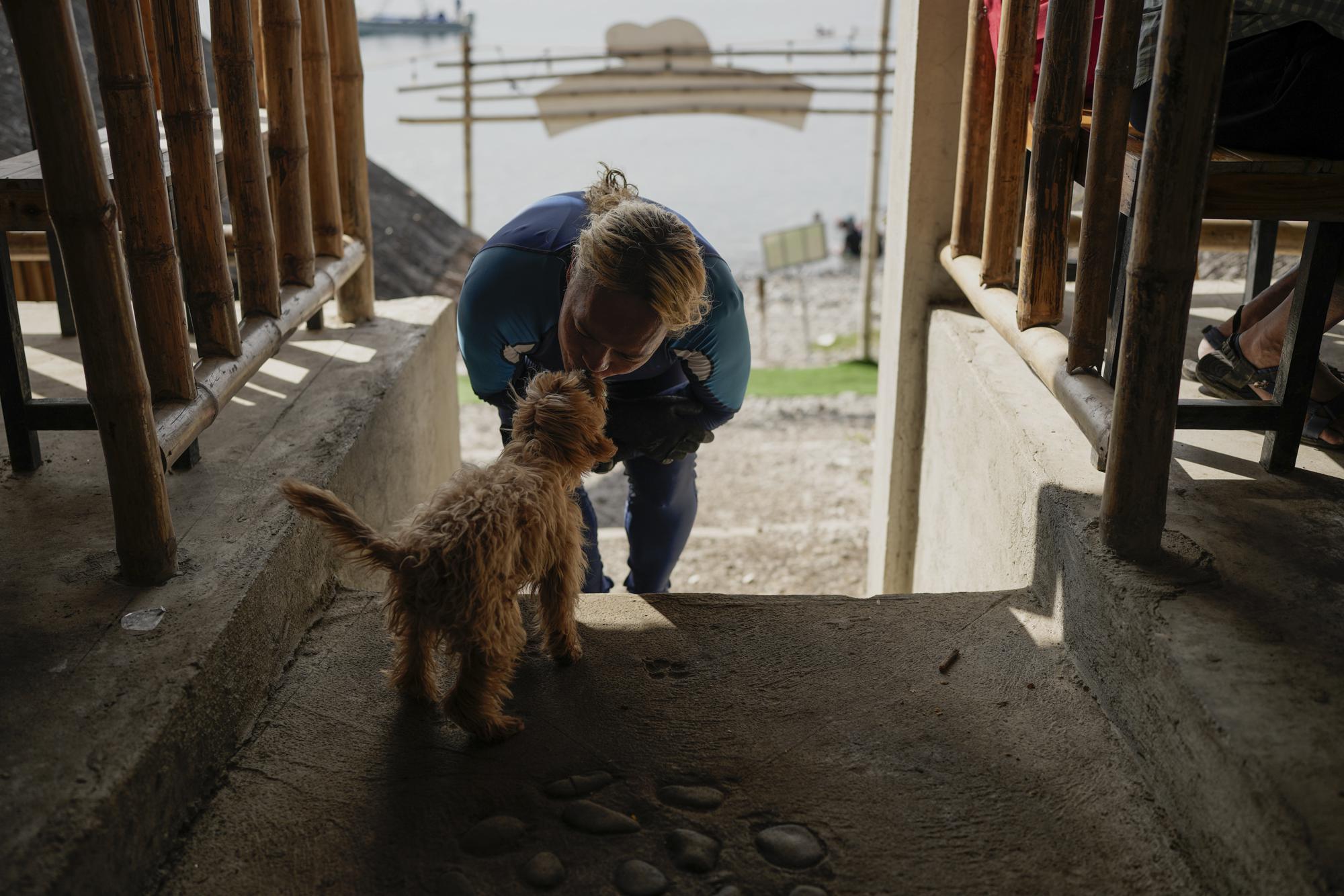 Queen Pangke Tabora kisses her dog "Choknut" before teaching freediving and mermaiding classes at the Ocean Camp in Mabini, Batangas province, Philippines on Saturday, May 21, 2022. (AP Photo/Aaron Favila)