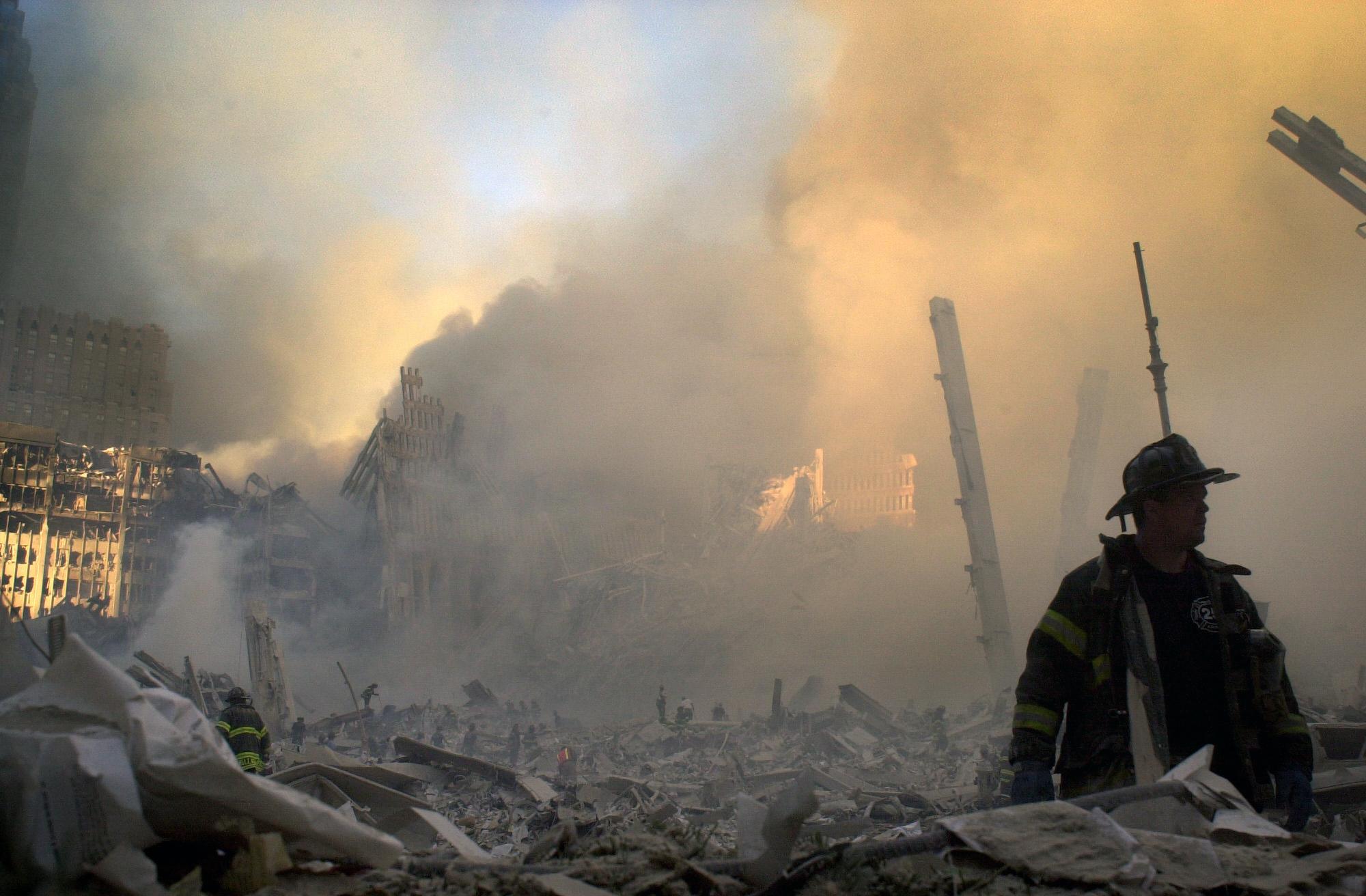 A firefighter moves through piles of debris at the site of the World Trade Center in New York, Tuesday, Sept. 11, 2001. (AP Photo/Graham Morrison)