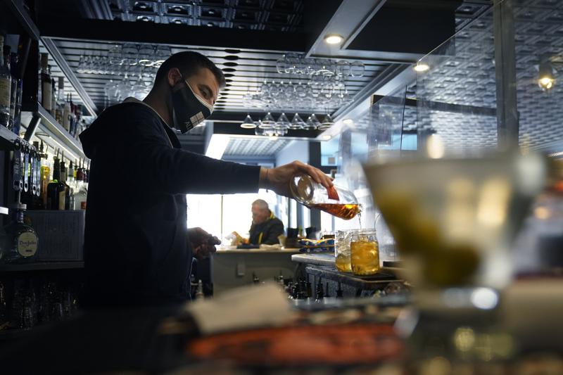 FILE - In this April 6, 2021, file photo, bartender Denis Angelov pours drinks at Tin Pan Alley restaurant in Provincetown, Mass. A study of a large coronavirus outbreak in Provincetown suggests the amount of virus in fully vaccinated people was as great as the viral load in unvaccinated people. Health officials released the study Friday, July 30, 2021, saying it explains their call this week for vaccinated people return to wearing masks indoors in parts of the U.S. where the delta variant of the coronavirus is fueling infection surges. The study focused on an outbreak this month in Provincetown, a seaside tourist spot located in the Massachusetts county with the state's highest vaccination rate. (AP Photo/Steven Senne, File)