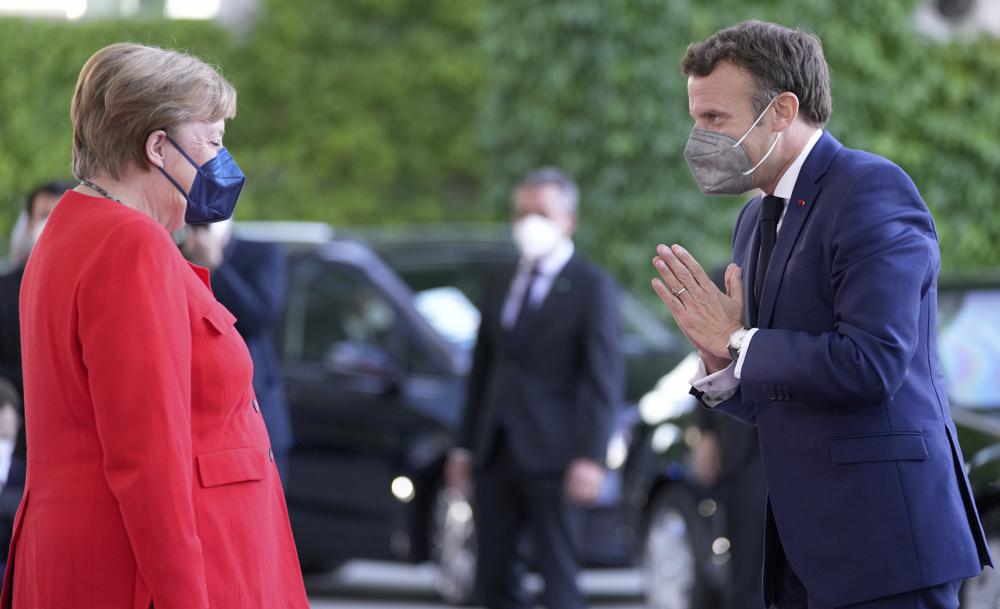 German Chancellor Angela Merkel, left, welcomes the President of France, Emmanuel Macron, right, for a meeting at the chancellery in Berlin, Germany, Friday, June 18, 2021. (AP Photo/Michael Sohn)