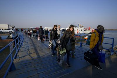 Refugiados que huyen de la guerra desde la vecina Ucrania caminan el jueves 24 de marzo de 2022 tras cruzar la frontera en ferry en el paso fronterizo de Isaccea-Orlivka, en Rumania. (AP Foto/Andreea Alexandru)