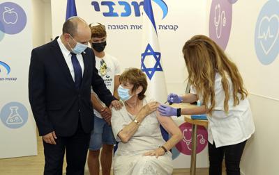El primer ministro israelí Naftali Bennett acompaña a su madre Mirna Bennett a ponerse la tercera vacuna contra el coronavirus en Haifa, Israel, el 3 de agosto del 2021. (Elad Gershgoren/Pool vía AP)