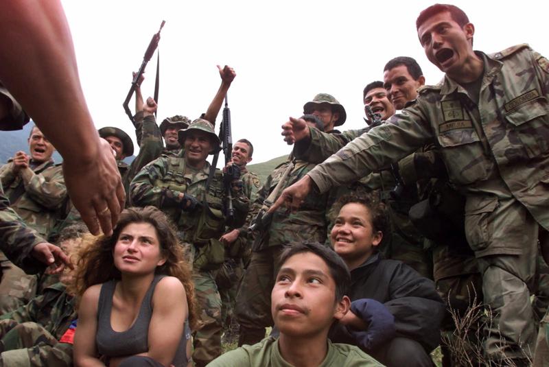 FILE - In this Dec. 21, 2000 file photo, soldiers guard three captured teenage rebels of the Revolutionary Armed Forces of Colombia, FARC, in the mountains of Santander state in northwestern Colombia. A Colombian tribunal that investigates war crimes said on Tuesday, Aug. 10, 2021, that the FARC recruited at least 18,600 children into its ranks between 1996 and 2016, when it made peace with the government. (AP Photo/Scott Dalton, File)