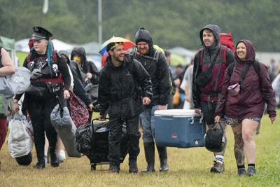 Asistentes a un festival de música llegan al recinto, bajo la lluvia, en el primer día del Download Festival, en Donington Park, Castle Donington, Inglaterra, el 18 de junio de 2021. (Joe Giddens/PA via AP)