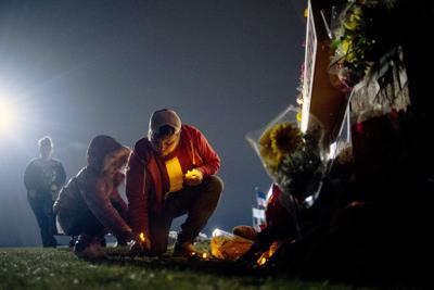 El residente de Waterford Andrew Baldwin, primo de Madisyn Baldwin, coloca velas a la base de un memorial con su hija de 5 años Ariyah Baldwin el 1 de diciembre del 2021, en Oxford, Michigan. Madisyn Baldwin, de 17 años, fue una de cuatro adolescentes muertos en el tiroteo escolar el 30 de noviembre. (Jake May / The Flint Journal vía AP)