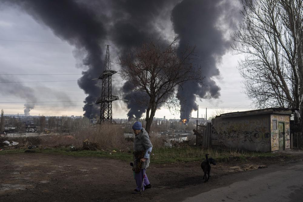 Una mujer camina mientras el humo se eleva en el aire de fondo después de un bombardeo en Odesa, Ucrania, el domingo 3 de abril de 2022. (Foto AP/Petros Giannakouris)