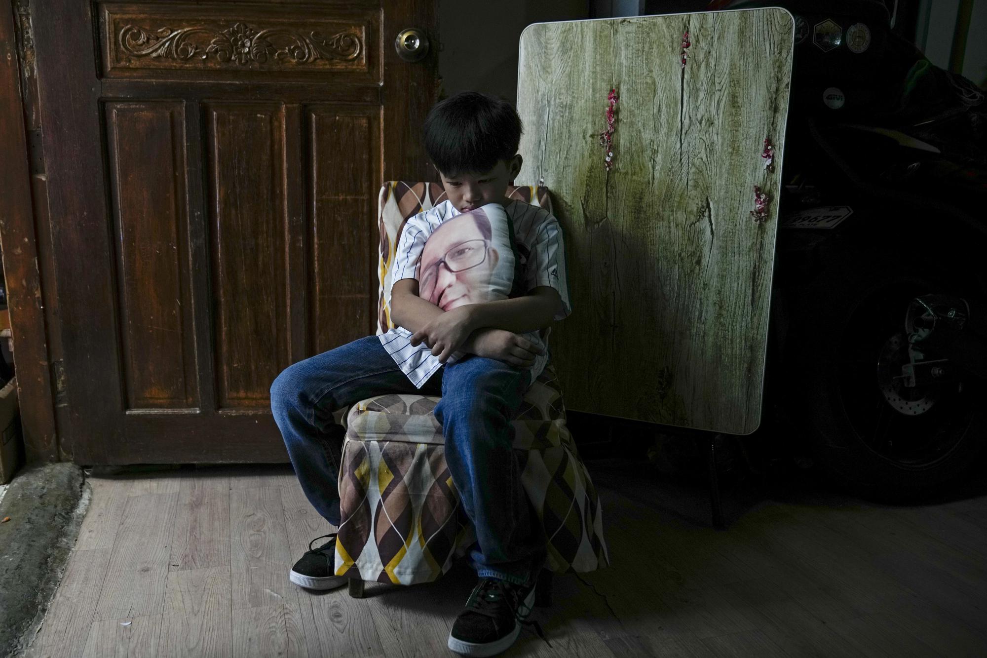 Kian Navales poses at home in Quezon city, Philippines, on Tuesday, July 6, 2021, holding a pillow with a photo on it of his late father, Arthur, who died from the coronavirus. Navales, who also had the virus, misses going out for noodles with his dad. (AP Photo/Aaron Favila)
