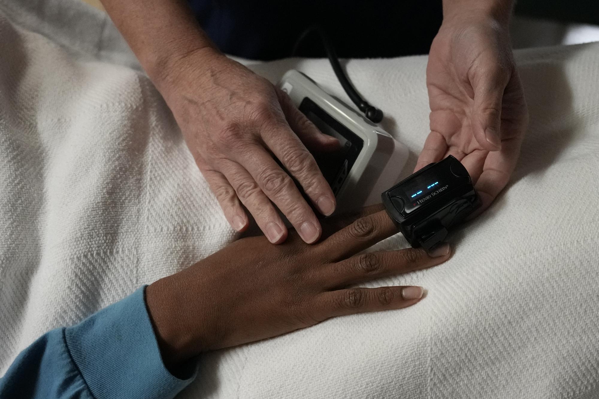 A nurse checks the vitals of a 33-year-old mother of three from central Texas as she rests after getting an abortion, Saturday, Oct. 9, 2021, at Hope Medical Group for Women in Shreveport, La. She said having another child at this point in her life would take away from her ability to care for her other three children, so she drove alone four hours through the night to make it to the clinic for her initial consultation. (AP Photo/Rebecca Blackwell)