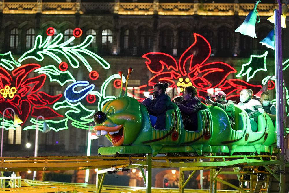 La gente visita un parque de diversiones inaugurado en el Zócalo como parte de la temporada navideña en Ciudad de México, el viernes 17 de diciembre de 2021. La famosa plaza de la capital fue decorada con un espectáculo de luces, nieve artificial y artistas locales actuando en el escenario. (Foto AP/Eduardo Verdugo)