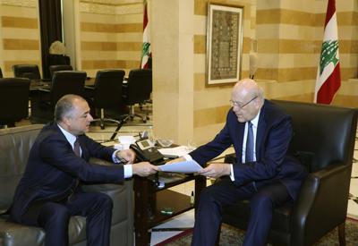 En esta imagen publicada por el fotógrafo oficial del gobierno libanés, Dalati Nohra, el primer ministro de Líbano, Najib Makati, a la derecha, recibe el borrador final del acuerdo de fronteras marítimas entre Líbano e Israel de manos de su número dos, Elias Bou Saab, que lidera el equipo negociador libanés, en Beirut, Líbano, el martes 11 de octubre de 2022. (Dalati Nohra via AP)